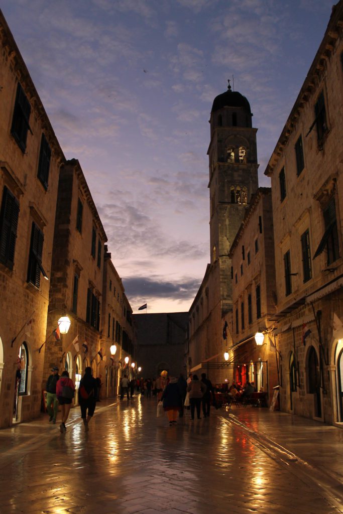 Dubrovniks Stradun street glows in the light of streetlights at dusk. Exploring Dubrovnik at night gets you away from the crowds and to nearly empty streets. Use this guide to Dubrovnik to find the other best things to do on your trip to the city. #Croatia