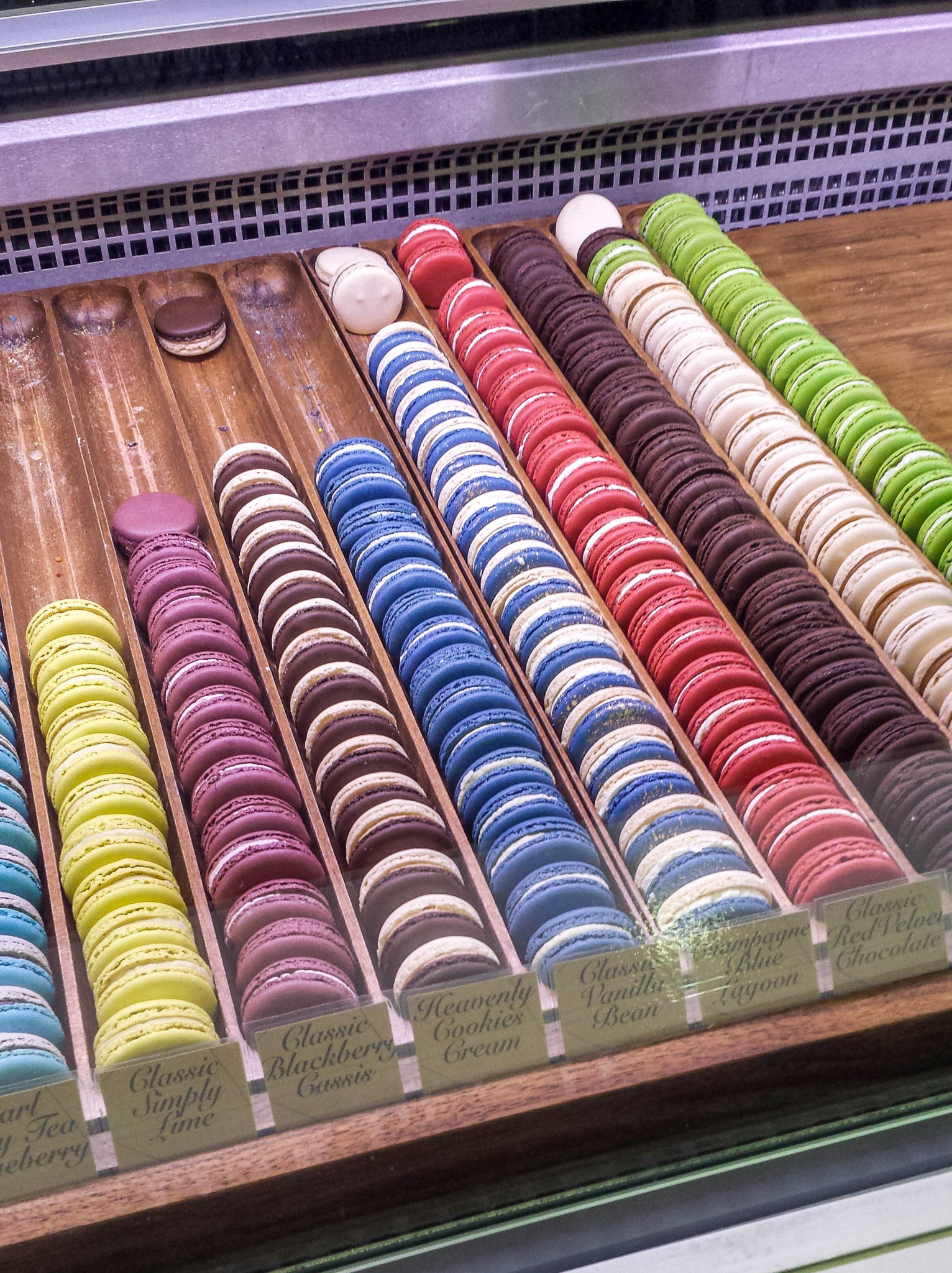 Multiple colours of macarons in rows on display at Delysees Toronto