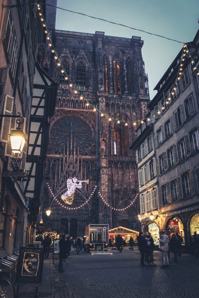 Street with Christmas lights and the gothic Strasbourg Cathedral in background, France. Strasbourg is a great day trip from Paris or a great addition to a one week France itinerary