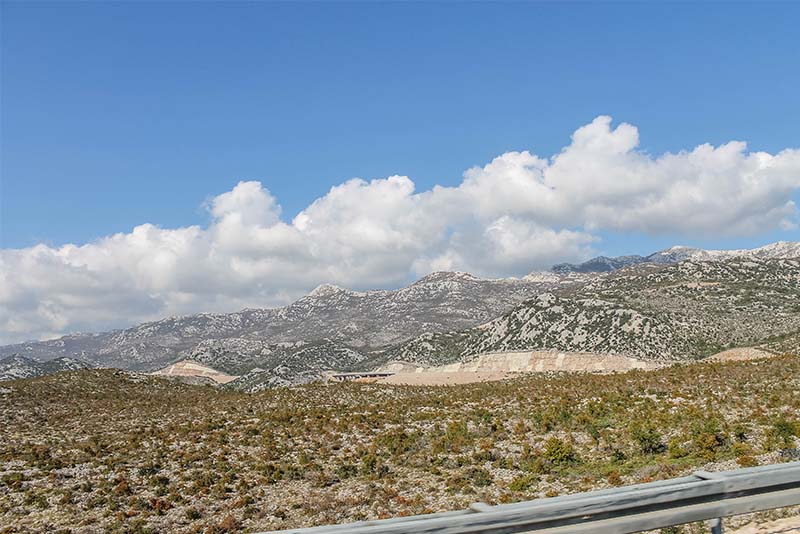 Driving into Zadar from the North, mountains and brushy landscape and a winding road in distance