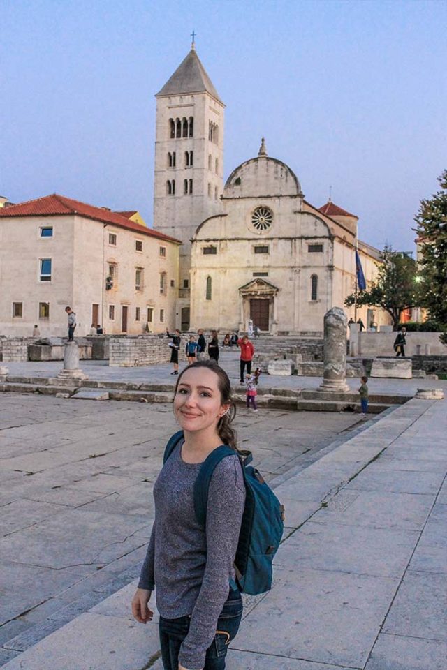 Woman standing in front of Zadar Croatia's Roman ruins including bell tower and church