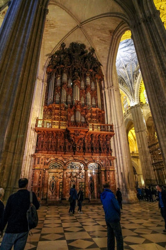 Huge arches of the gothic Seville cathedral and the large organ that is inside.