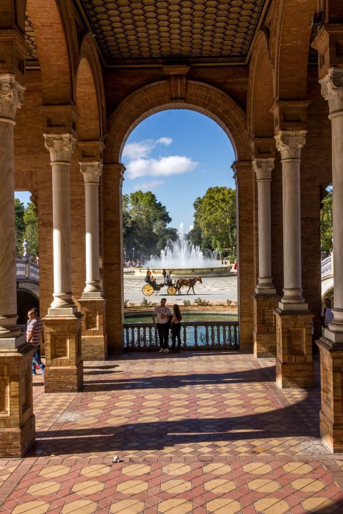 View of the arches with the fountain and a horse carriage in the background at the Plaza de Espana, Seville