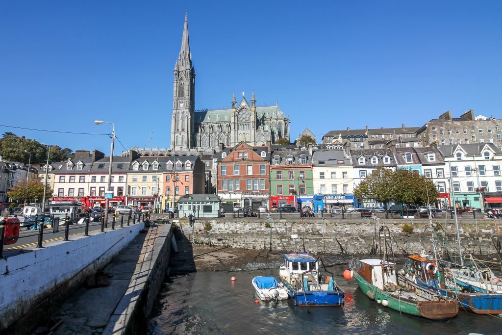 Cobh with colorful shops, harbor, and St.Colman's Cathedral sitting on a hill behind it all.