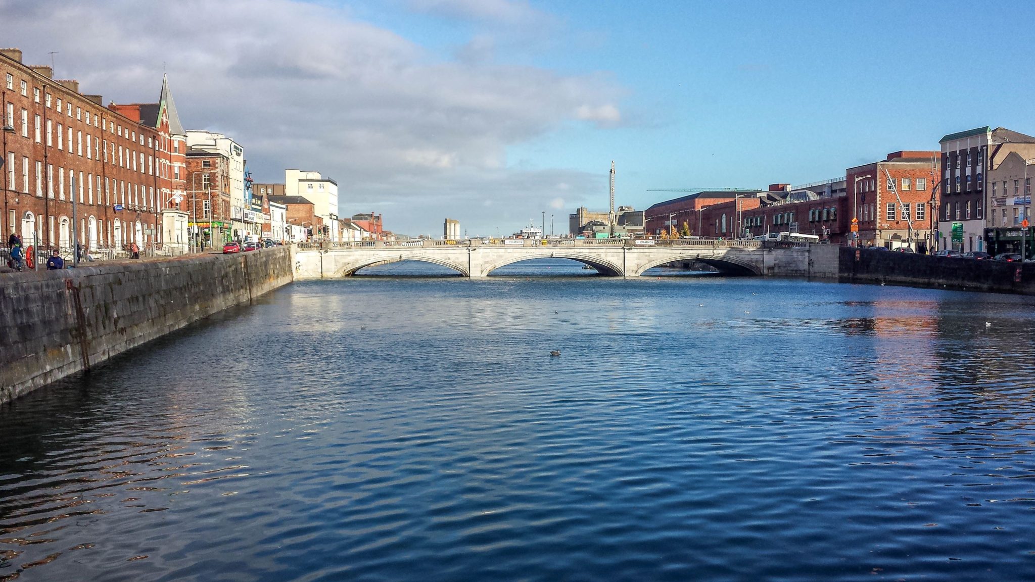The River Lee in Cork Ireland with brick buildings on both sides and a bridge in the distance