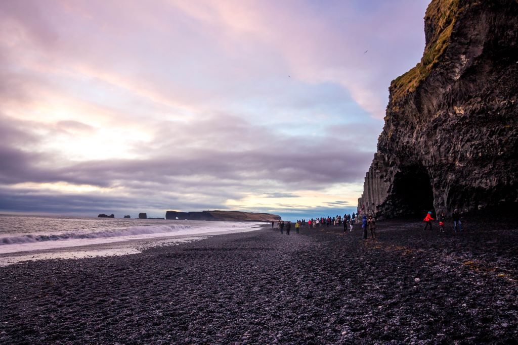 Sunset over Reynisfjara black sand beach in Vik, Iceland with Dyrholaey arch in the background.