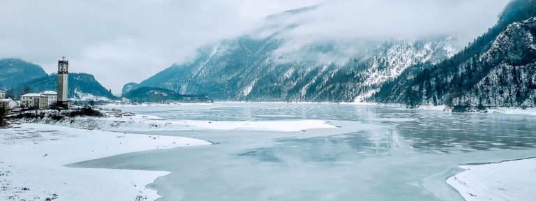 Frozen lake with mountains behind it during the winter. The best places to ice skate in the world with the most beautiful scenery and settings.