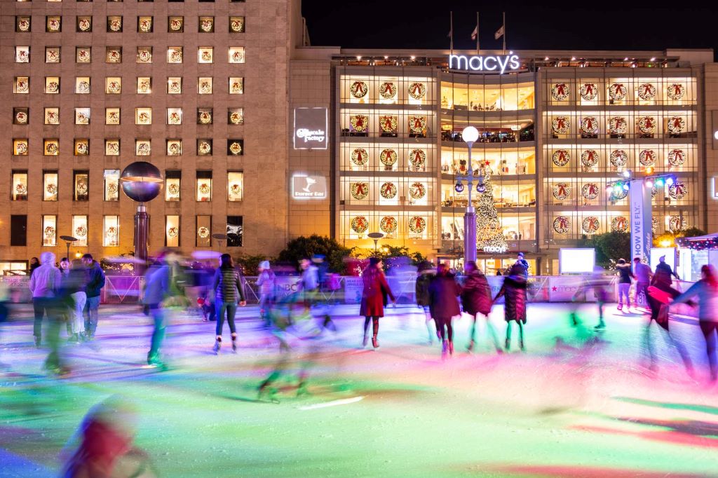 Colorful lights on the Union Square skating rink in San Francisco, USA with Macy's lit up behind it with holiday wreaths in every window. San Francisco is a great city to skate in with multiple skating rinks and lots of Christmas lights.
