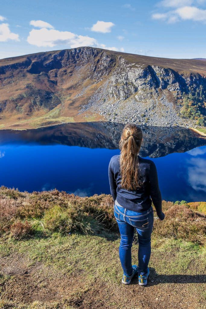 Woman stands with back to camera in front of a lake in Ireland