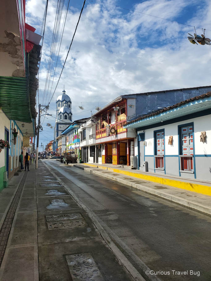 Street in Filandia, Colombia after rain with a white and blue church in the background.