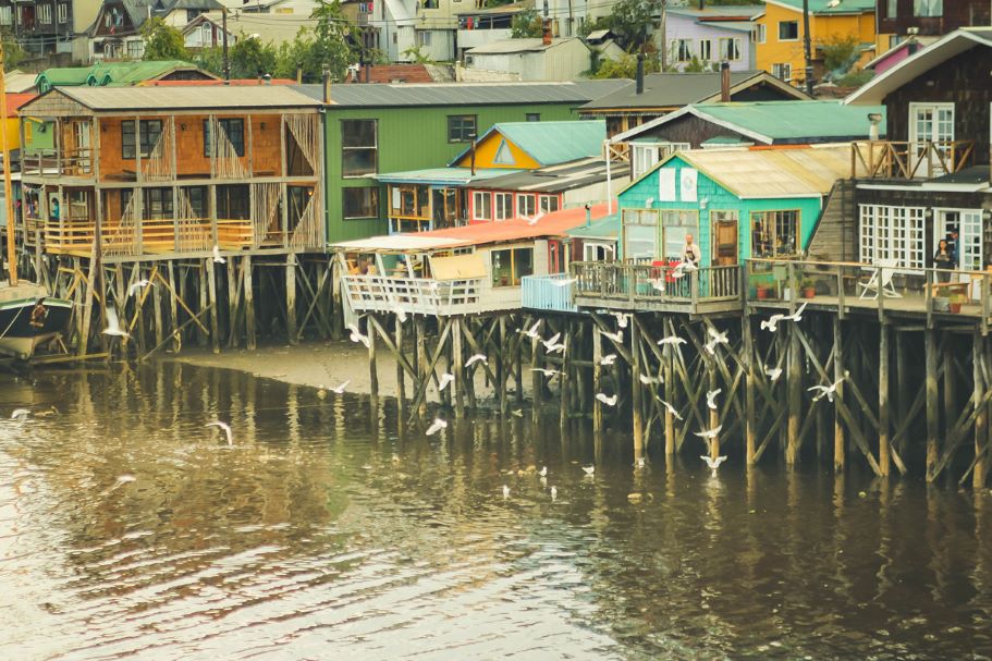Chiloe Island in Chile with houses and shops built on stilts above the water. This island is a unique island in South America to visit because it has a unique culture and wildlife to view.