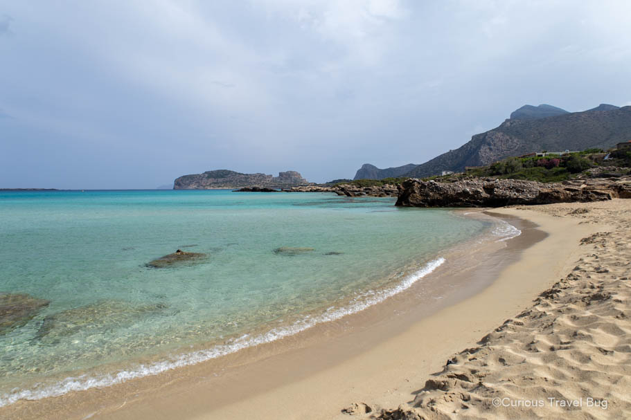 Falasarna Beach with views of the mountains and Balos Bay. There is some pink sand to be found amongst the golden sand here as well and is a fantastic beach in Crete to swim and relax on.