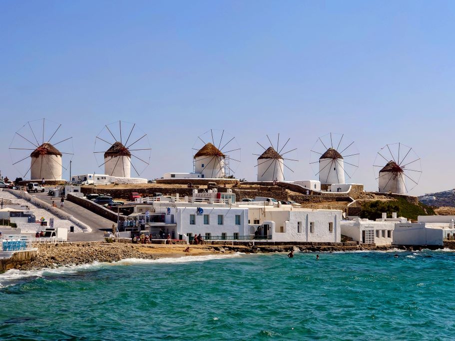 Sea with white buildings and traditional windmills on Mykonos, Greece