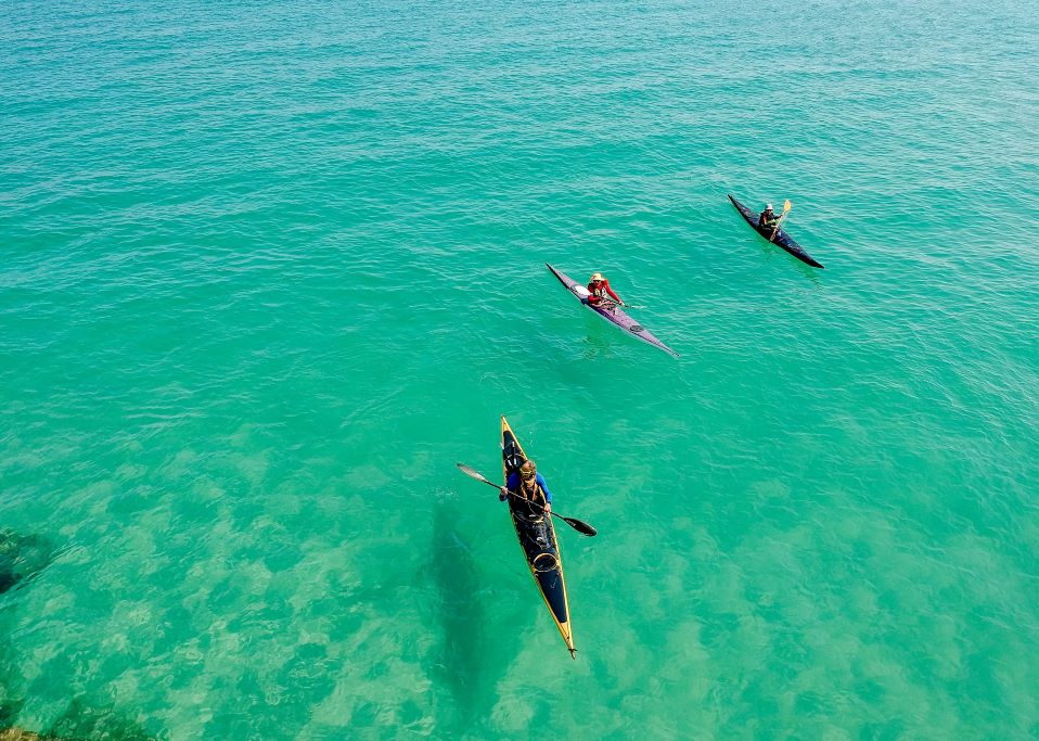 Three sea kayaks on turquoise water. Go sea kayaking on a day trip from Athens to explore the southeast coast