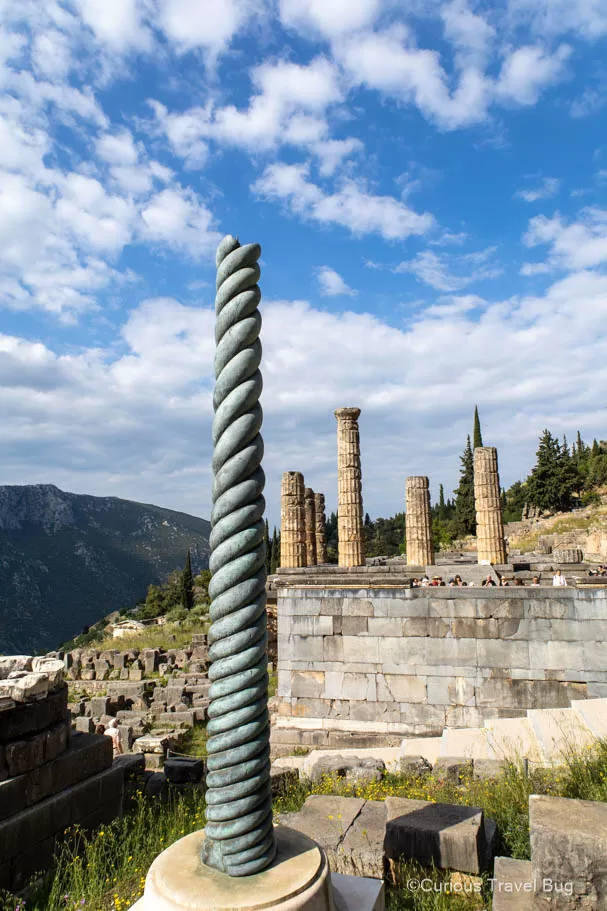 Replica of the Serpent Column with the Temple of Apollo in the background. The original was topped with the head of three serpents and each coil of the column was dedicated to a different Greek city state that fought at the battle of Plataea