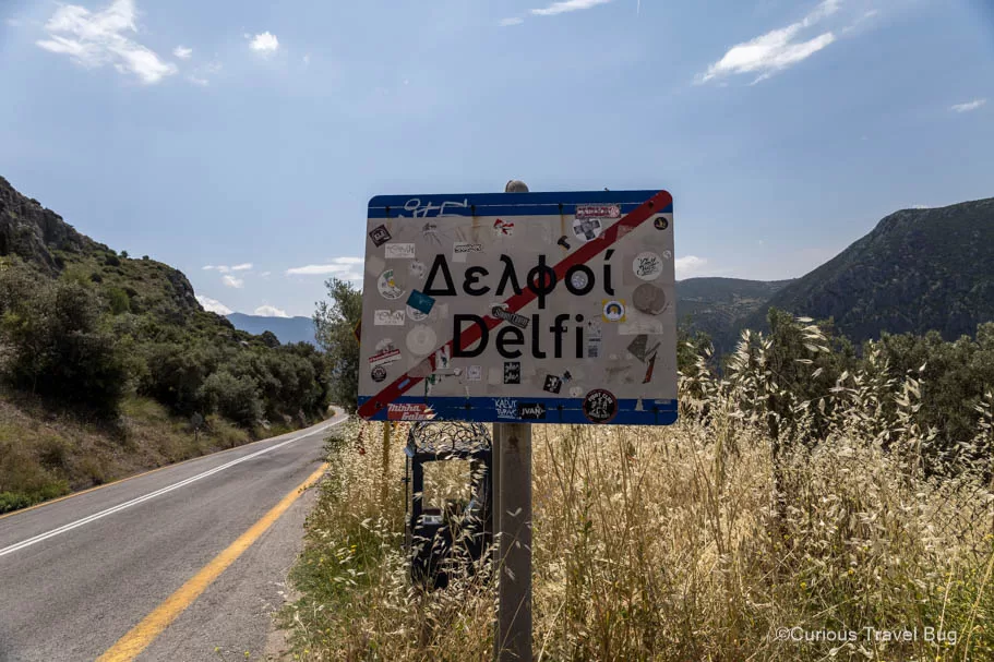 Sign that indicates leaving Delphi, Greece with Mount Parnassus in the background