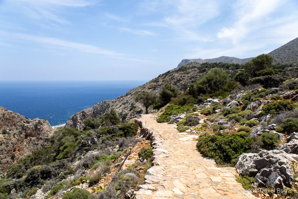 A cobblestone path that leads down to Katholiko Monastery with stunning views of the Sea of Crete and mountains.