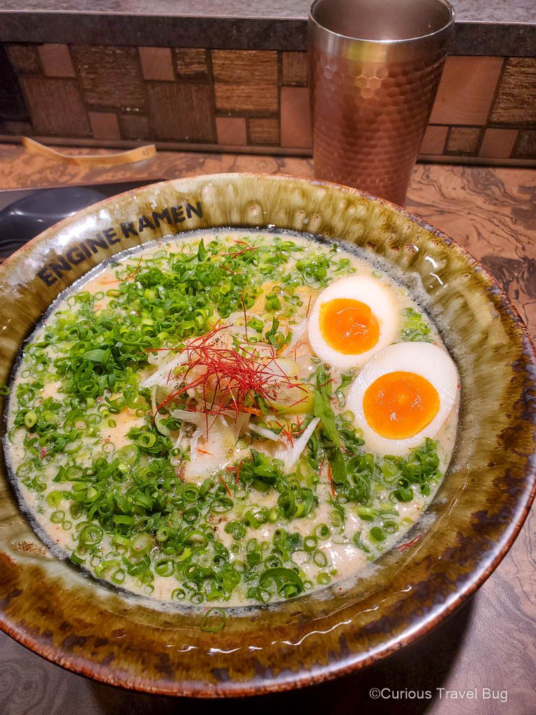 A bowl of ramen topped with plenty of green onions and a couple of soft boiled eggs